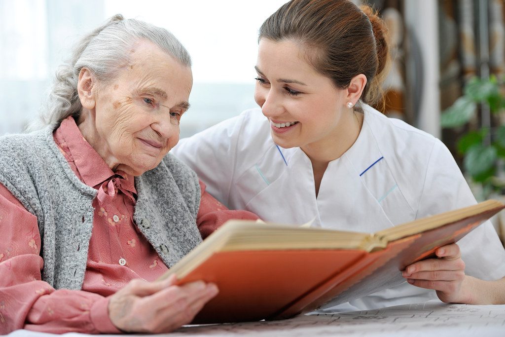 Cuidadora leyendo junto a una señora mayor